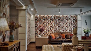 A living room with a patterned wallpaper, a sofa, a coffee table, and a lamp. - Gala (Noja)