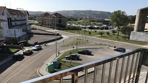 Un edificio de varios niveles con un cartel de hotel visible, una glorieta con coches y vistas a un paisaje montañoso.