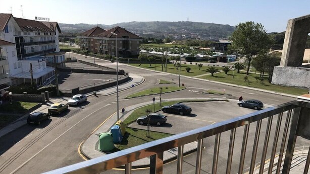 A multi-level building with a visible hotel sign, a roundabout with cars, and a view of a hilly landscape. - Gala (Noja)