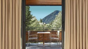 A balcony with two chairs and a table, overlooking a mountainous landscape. - NH Collection Andorra Palome (Arinsal)