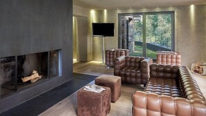 A modern living room with a fireplace, leather sofas, and a flat-screen TV. - NH Collection Andorra Palome (Arinsal)