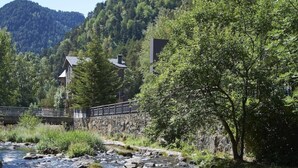 Un río con rocas, un puente y edificios en una zona boscosa.
