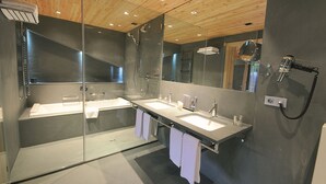 Un baño moderno con dos lavamanos, una cabina de ducha con mampara de vidrio y un secador de pelo montado en la pared.