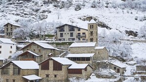 A snow-covered village with stone buildings, including a prominent tower. - NH Collection Andorra Palome (Arinsal)