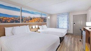 Una habitación de hotel con dos camas, un cuadro de follaje otoñal, una cortina estampada y una puerta.