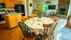 Un comedor con una mesa redonda cubierta con un mantel estampado de flores, rodeada de sillas de madera.