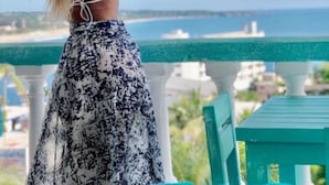 A person standing on a balcony with a view of the sea and buildings in the background. - Hotel Costa 55 (Puerto Escondido)