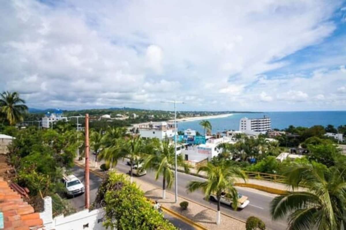 A coastal cityscape with a road, buildings, and a beach.