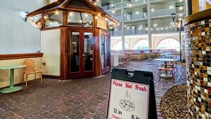 An indoor dining area with a brick floor, a signboard detailing pizza toppings, and a multi-level seating area with string lights. - Spacious 9th floor, 2 bedroom plus bunkroom with STUNNING OCEAN & POOL VIEWS! (Panama City Beach)