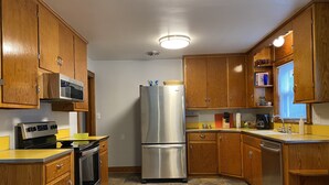 A kitchen with wooden cabinets, a stainless steel refrigerator, a microwave, and a stove.