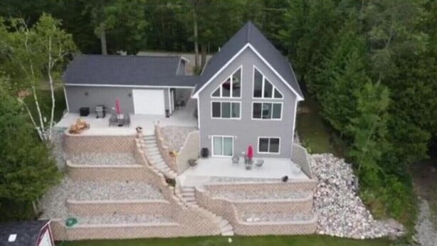 Ein zweistöckiges Haus mit großer Terrasse, Garage und gepflegtem Rasen.