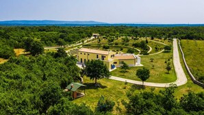 An aerial view of a property with a central building surrounded by landscaped gardens and a winding road. - Modern 5-BR villa for 10+1 with heated pool and specious land (Filipana)