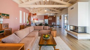 A spacious living room with a large sectional sofa, a wooden coffee table with fruit, and a fireplace. - Modern 5-BR villa for 10+1 with heated pool and specious land (Filipana)