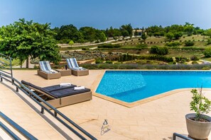 A poolside area with lounge chairs, a small pool, and a view of a landscaped garden. - Modern 5-BR villa for 10+1 with heated pool and specious land (Filipana)