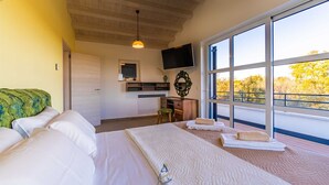 A bedroom with a large bed, a TV, a window with a view of trees, and a wooden ceiling. - Modern 5-BR villa for 10+1 with heated pool and specious land (Filipana)
