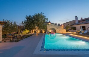 A swimming pool with lounge chairs and a stone archway.