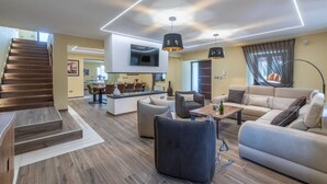 Una sala de estar moderna con una escalera, un comedor y una cocina.