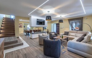 Ein modernes Wohnzimmer mit Treppe, Essbereich und Küche.