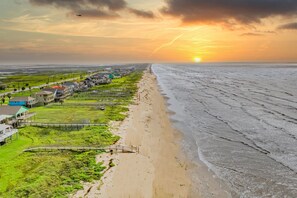 A coastal view with a beach, a boardwalk, and buildings along the shore.