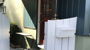 Un portico riparato con una porta rossa, un tavolino e un tappeto decorato.