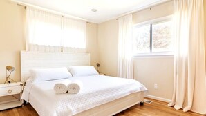 A bedroom with a bed, a nightstand, a lamp, and a window with curtains. - 5 bedrooms with 4 Full Bath, Fire Pit,  BBQ and Plush Amen on 1/2 acre (Silver Spring)
