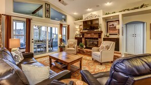 A spacious living room with a fireplace, leather sofas, and a ceiling fan. - The Retreat at Thumb Butte (Prescott)