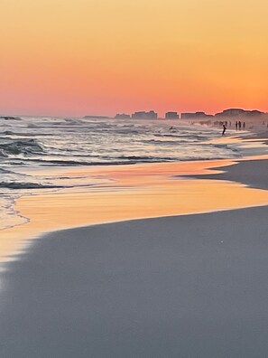 A beach with waves and a sunset.