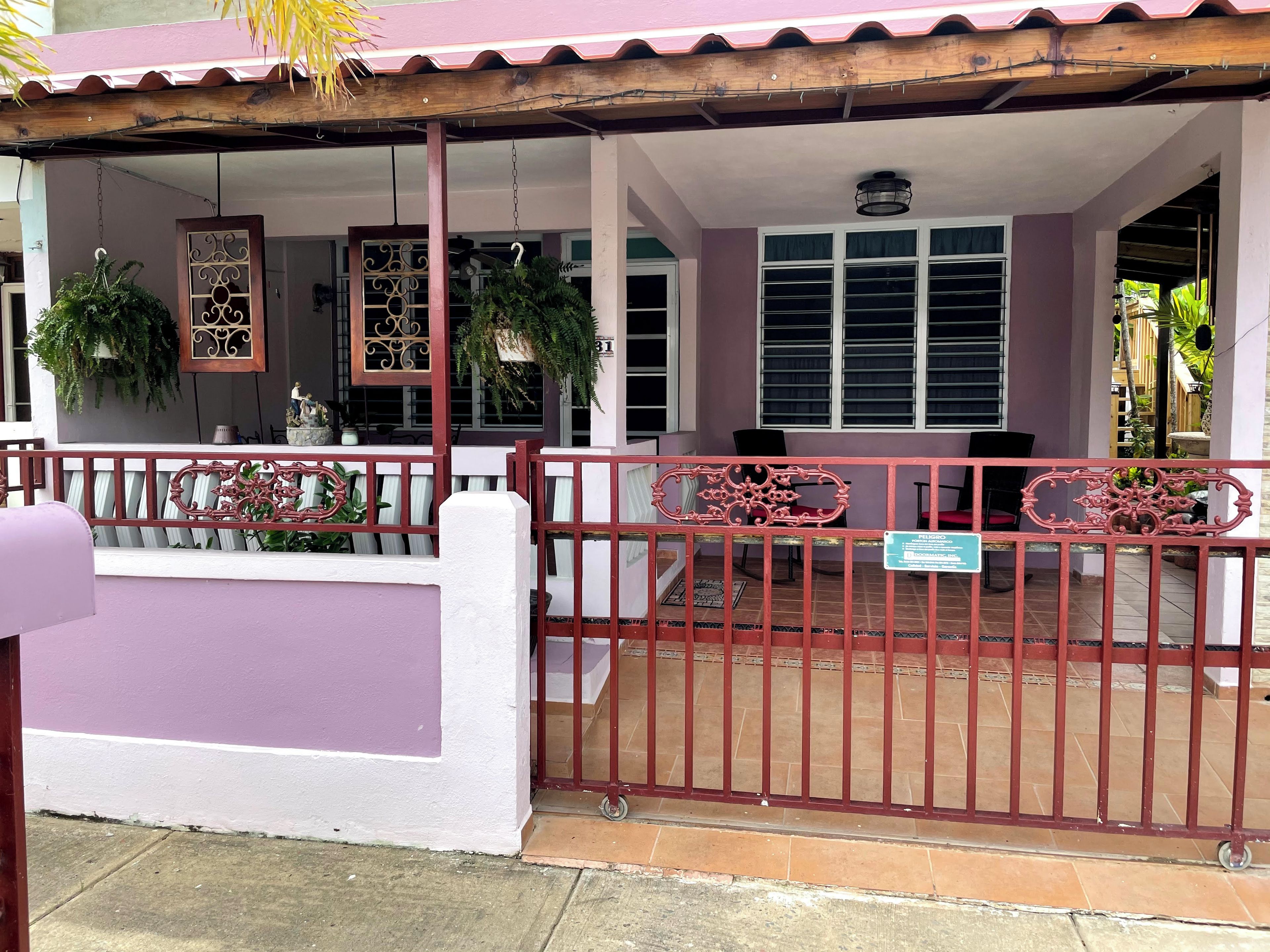 A building with a covered porch, a gated entrance, and a sign indicating a public space.