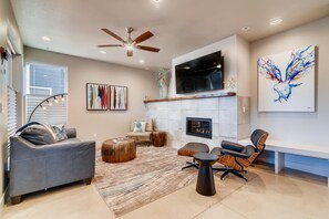 A modern living room with a fireplace, comfortable seating, and artwork on the walls.