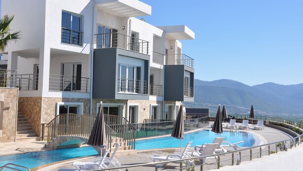 Ett modernt hotell med flera våningar och en takpool som ser ut att gå över kanten, med en fantastisk panoramautsikt över bergen.