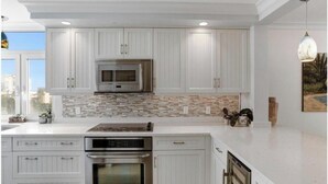 A modern kitchen with white cabinetry, a stainless steel range, and a microwave. - Ocean front , beach views - exquisite sunsets and relaxing setting. (Naples)