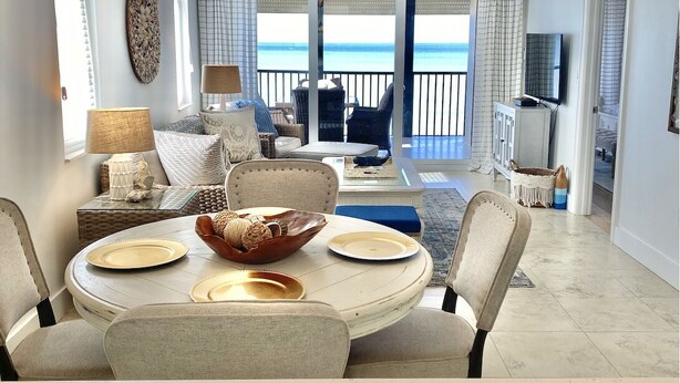 A spacious living area with a dining table set, a ceiling fan, and a view of the ocean. - Ocean front , beach views - exquisite sunsets and relaxing setting. (Naples)