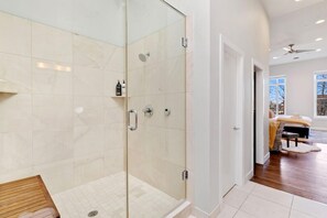 A modern bathroom with a glass-enclosed shower, a wooden bench, and a visible toilet. - THE PENTHOUSE loft in the heart of Old Town! (Fort Collins)