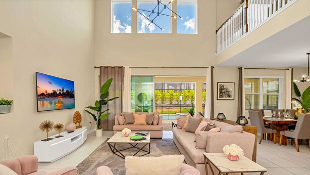 A spacious living room with a large sofa, a coffee table, and a dining area with a table and chairs. - Luxurious Villa With Modern Decor and Huge Pool in Upscale Resort! #6s820 (Kissimmee)