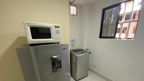 A compact kitchen with a refrigerator, a microwave, and a water dispenser. - Cute 1 room apartment Laureles (Medellín)