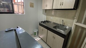 A compact kitchen with a stove, sink, and cabinets. - Cute 1 room apartment Laureles (Medellín)