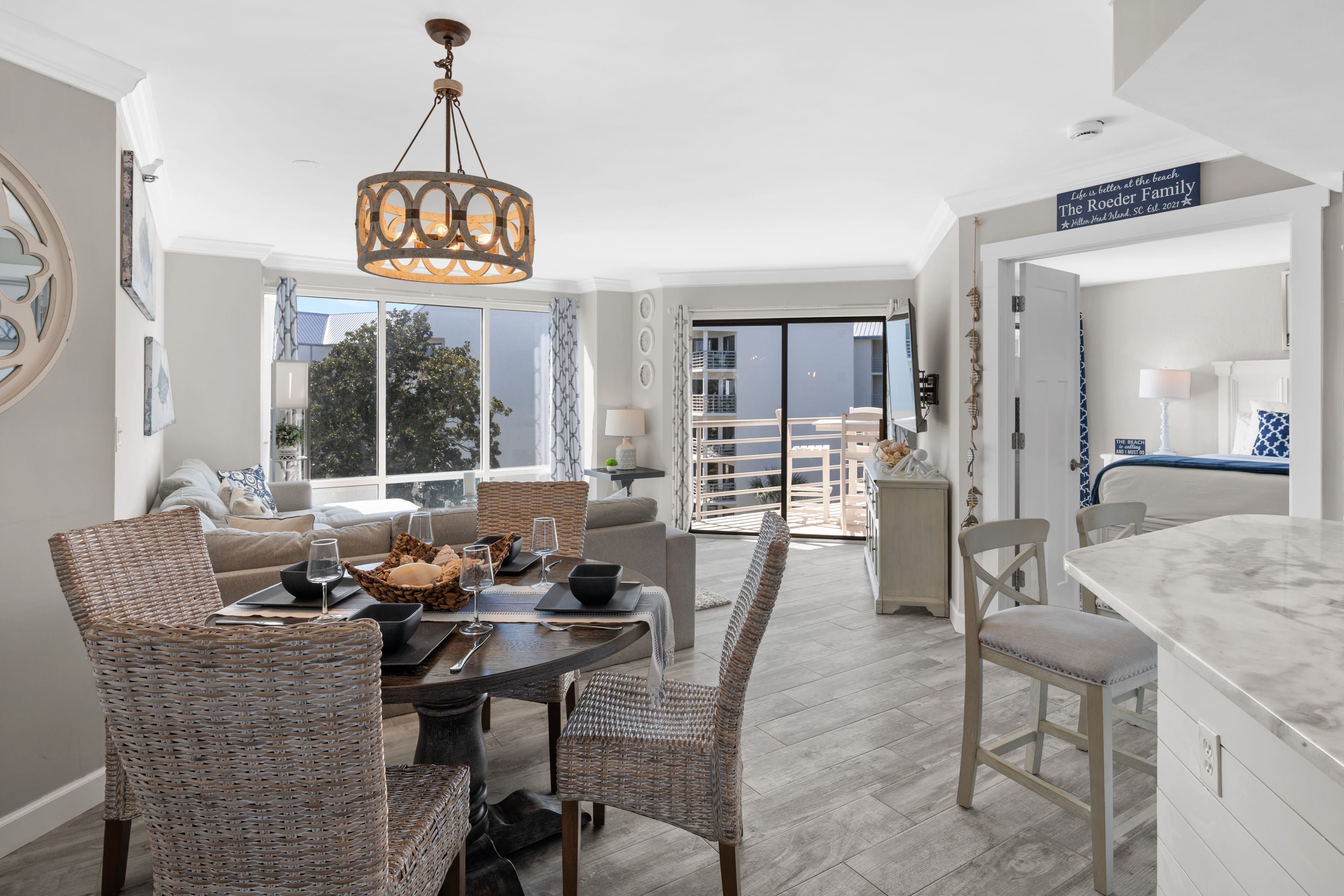 Un salon moderne avec un coin repas, un lustre et une vue sur l’extérieur.