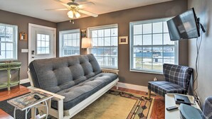 A living room with a sofa, a chair, a TV, and a ceiling fan. - Downtown Boyne City Home, Walk to Lake Charlevoix! (Boyne City)