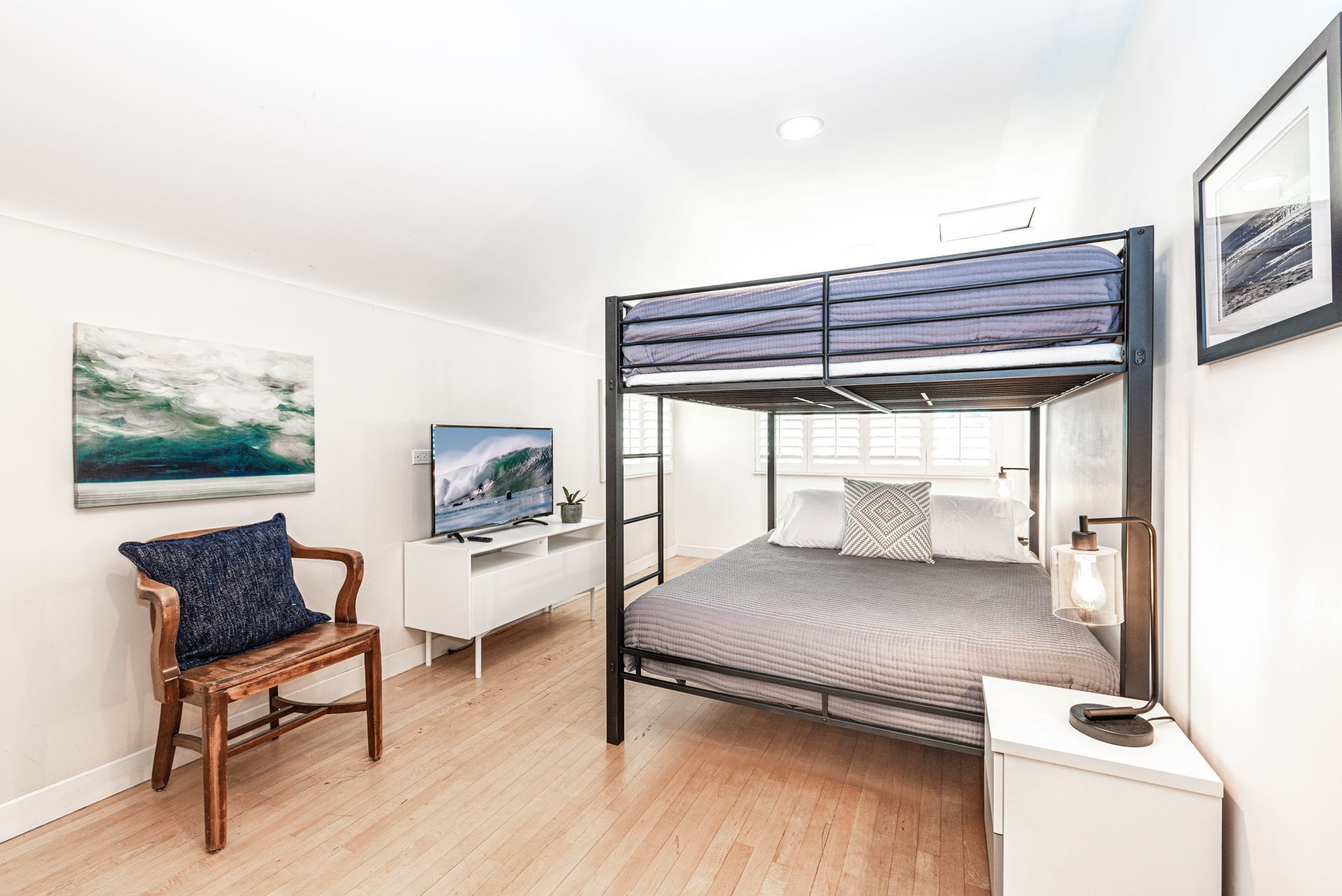 A bunk bed room with a desk, chair, and artwork.