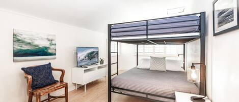 A bunk bed room with a desk, chair, and artwork.