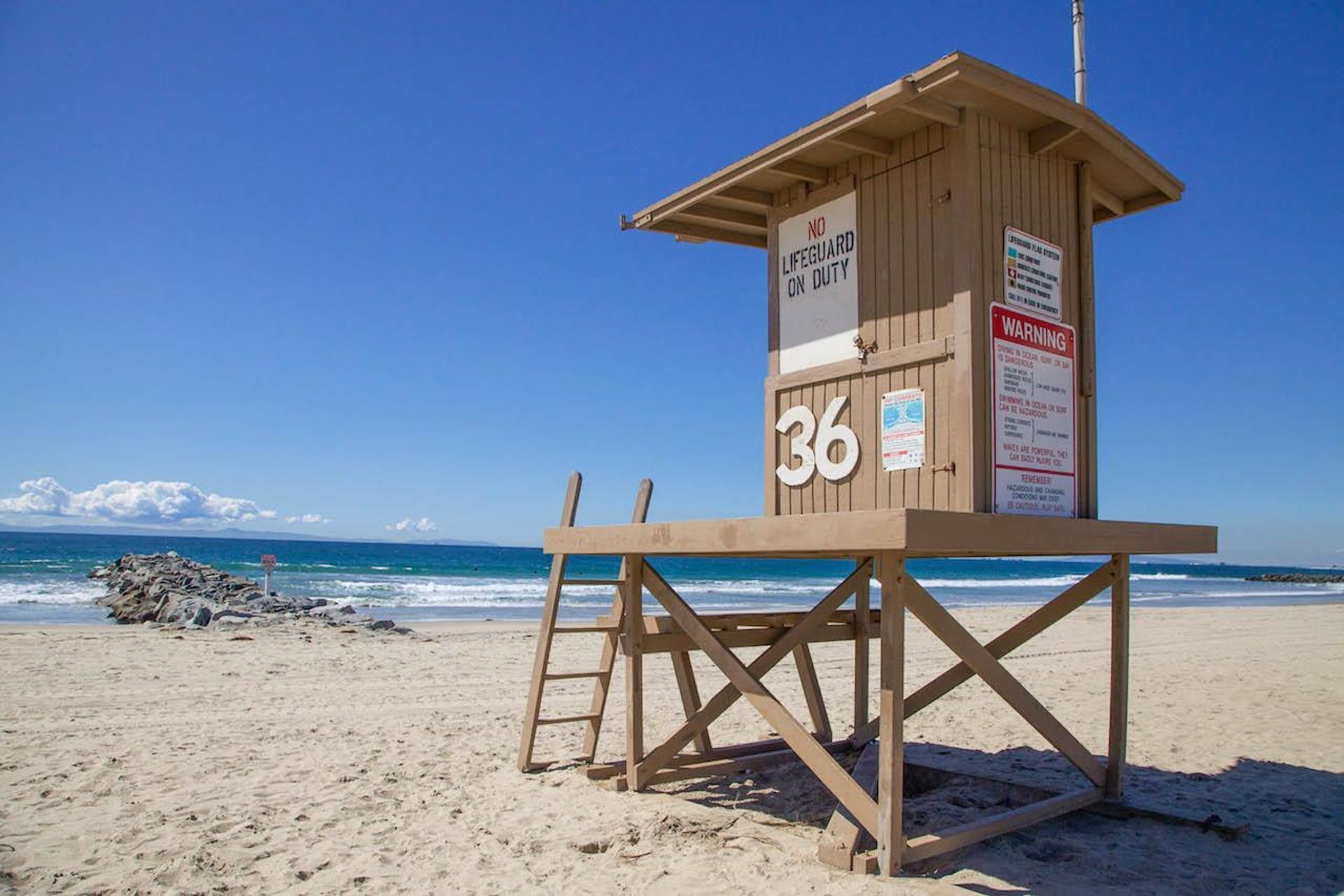 A lifeguard tower with the number 36, located on a sandy beach with the ocean in the background.