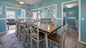 Un comedor con una mesa y sillas de madera, un tapete colorido y una escalera que conduce a otra habitación.