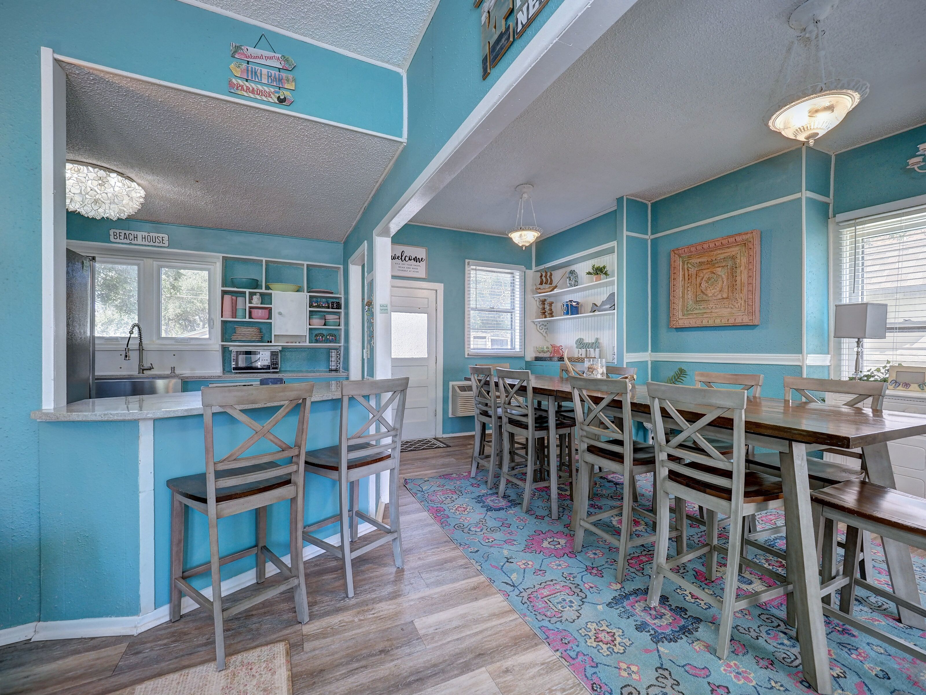 Una cocina con microondas, lavamanos y un cartel que dice 'BEACH HOUSE'.