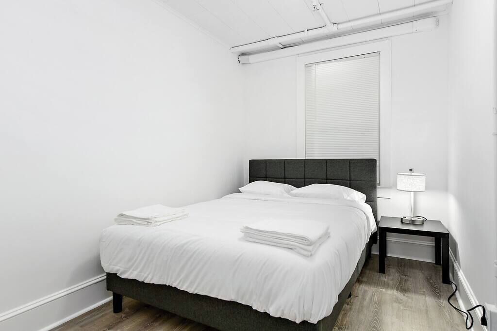 A minimalist bedroom with a bed, bedside table, and a window.