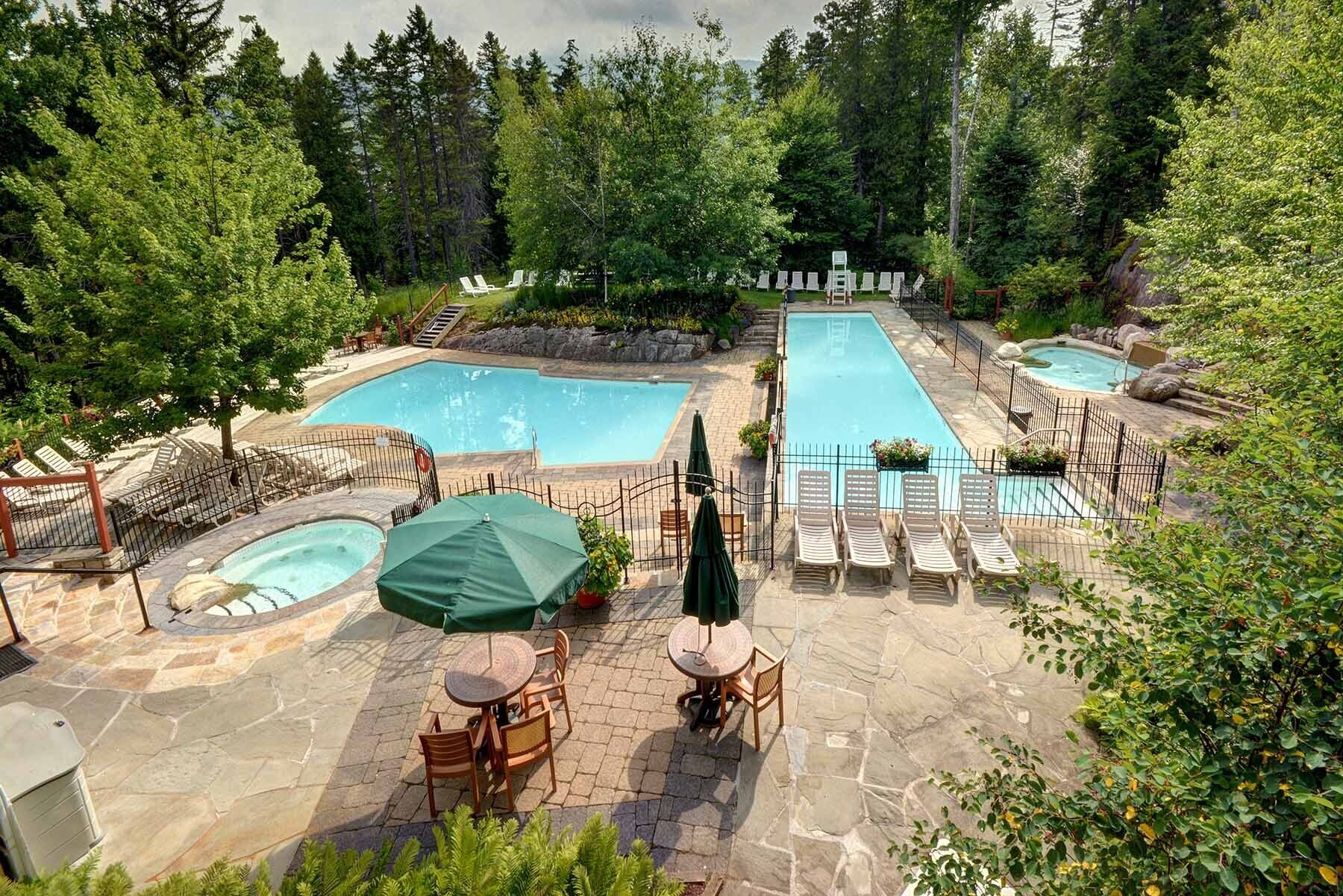 A pool area with two pools, lounge chairs, and a hot tub.