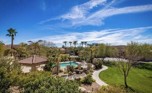 A residential area with a swimming pool, palm trees, and a gazebo.