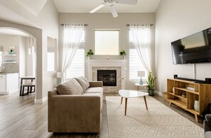 A modern living room with a fireplace, a sofa, a TV, and a dining area.