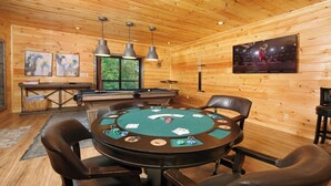 Un interno in legno con un tavolo da poker, sedie, un biliardo e opere d'arte alle pareti.