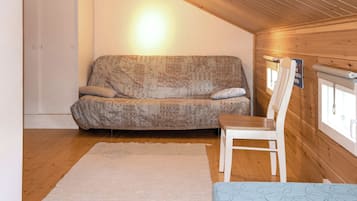 Una habitación acogedora con un sofá, una silla, un tapete y techo de madera.