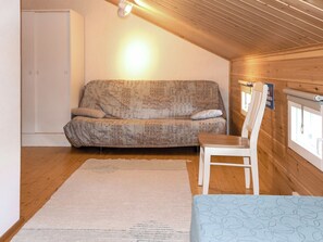 Una habitación acogedora con un sofá, una silla, un tapete y techo de madera.